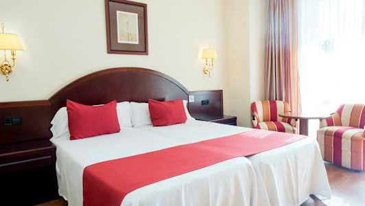 Dobbeltrom med rød innredning og to lenestoler. (AI-generert tekst)