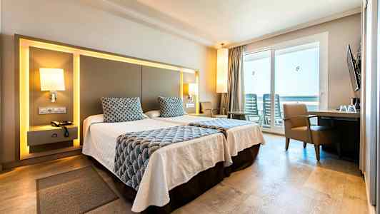 Et hotellrom med to enkeltsenger, moderne møbler og en balkong med utsikt. (AI-generert tekst)