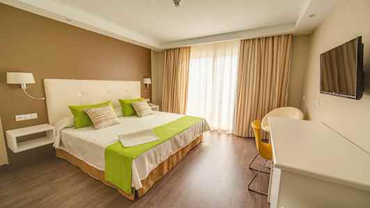 Hotellrom med dobbeltseng, grønne detaljer og moderne interiør. (AI-generert tekst)