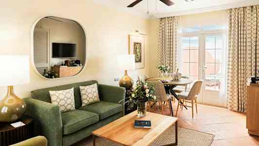 En stue med sofa, sofabord, spiseplass og glassdører som fører til en terrasse. (AI-generert tekst)