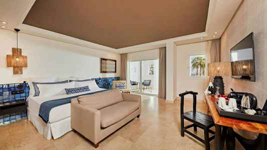 Hotellrom med dobbeltseng, sofa, skrivebord, TV og balkong. (AI-generert tekst)