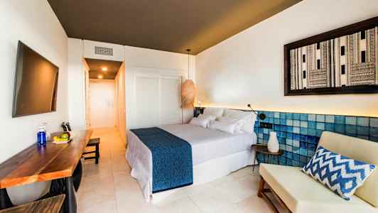 Moderne hotellrom med dobbeltseng, bord med frukt og en stol. (AI-generert tekst)