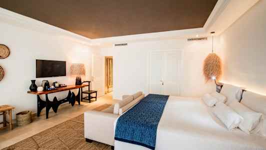 Et moderne hotellrom med en stor seng og en sittegruppe, samt en TV og et bord med kaffemaskin. (AI-generert tekst)