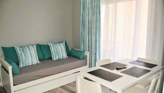 Stue med hvit dagseng og spisebord med fire stoler. (AI-generert tekst)