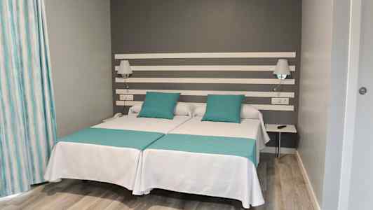 Dobbeltrom med to enkeltsenger og grå vegg. (AI-generert tekst)