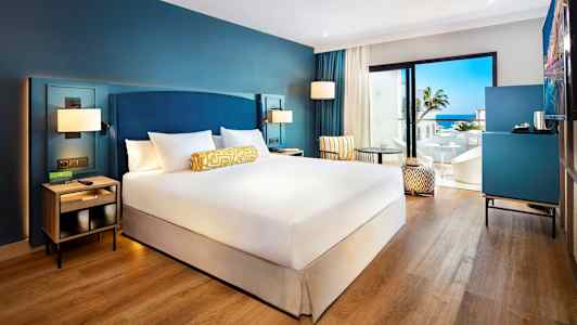 Hotellrom med dobbeltseng, sittemøbler og utsikt mot havet. (AI-generert tekst)