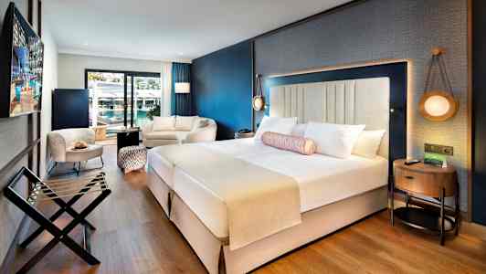 Moderne hotellrom med dobbeltseng, sittegruppe og balkong. (AI-generert tekst)