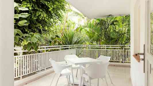 Terrasse med hvite hagemøbler omgitt av vegetasjon. (AI-generert tekst)