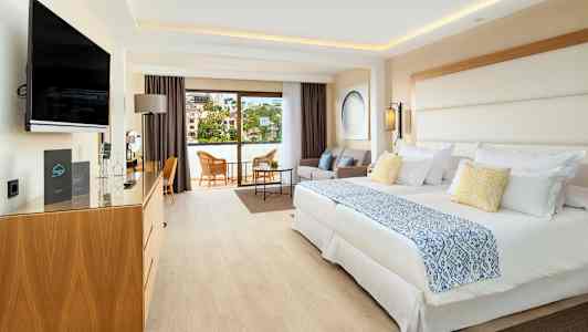 Et hotellrom med to senger, sittegruppe og balkong. (AI-generert tekst)