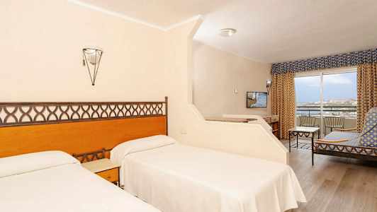 Hotellrom med to enkeltsenger, sittegruppe og balkong. (AI-generert tekst)