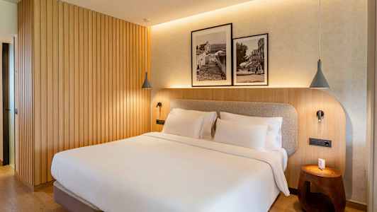 Et soverom med en dobbeltseng, trevegg og to innrammede svart-hvitt bilder over sengen. (AI-generert tekst)