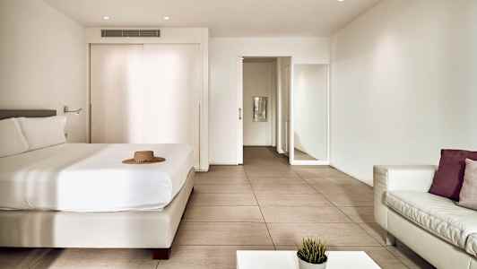 Et moderne hotellrom med en seng, sofa og bord. (AI-generert tekst)