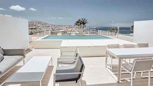 Terrasse med møbler, utsikt over bassenget og havet i bakgrunnen. (AI-generert tekst)