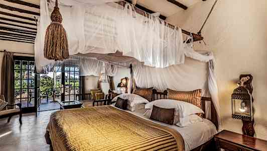 Et soverom med gjennomtenkt innredning, dobbeltseng med himmelseng og utgang til terrasse. (AI-generert tekst)