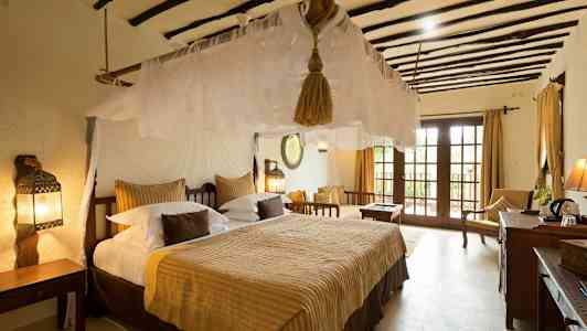 Et soverom med en stor seng, myggnett og tradisjonelle møbler. Vinduer med utsikt. (AI-generert tekst)