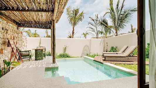 Terrasse med lite basseng, solsenger og vegetasjon under en trepergola. (AI-generert tekst)