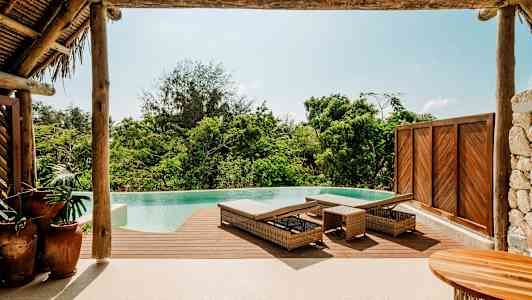 Et infinitybasseng med tredekke og solsenger i tropiske omgivelser. (AI-generert tekst)