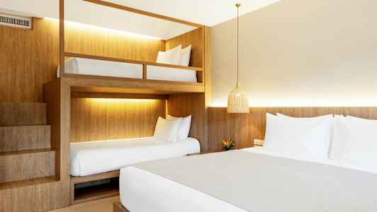 Et hotellrom med en dobbeltseng og køyesenger. (AI-generert tekst)