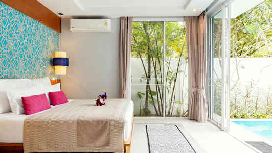 Et soverom med dobbeltseng, fargerike puter, stilfull innredning og utsikt mot et basseng og en hage. (AI-generert tekst)