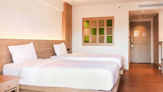 To enkeltsenger på et hotellrom med tregulv og lyst interiør. (AI-generert tekst)