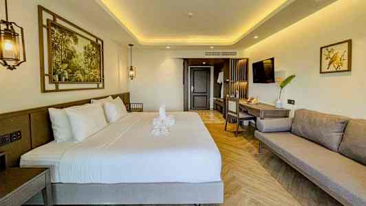 Moderne innredet hotellrom med dobbeltseng, sofa og arbeidsområde. (AI-generert tekst)