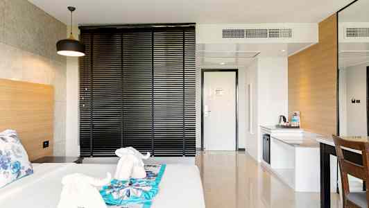 Hotellrom med seng, dekorert med håndklær formet som elefanter, og en arbeidsflate. (AI-generert tekst)