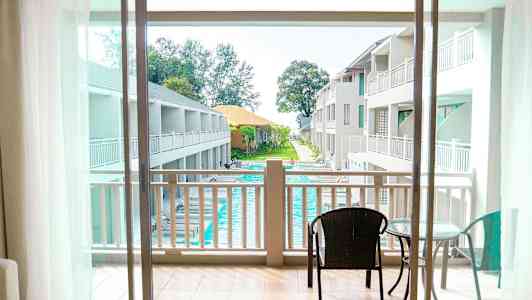 Utsikt fra balkong mot bassengområde og hotellbygninger. (AI-generert tekst)