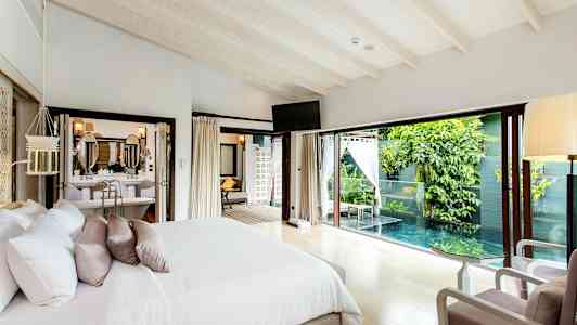 Soverom med dobbeltseng som har et vindu mot et privat basseng og grøntområder. (AI-generert tekst)