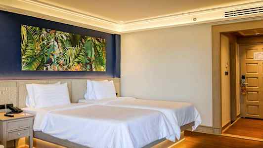 Hotellrom med to senger og et fargerikt bilde på veggen. (AI-generert tekst)