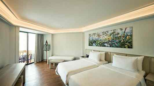 Hotellrom med to enkeltsenger, sitteplass og balkong. (AI-generert tekst)