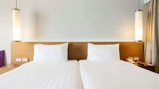 To enkeltsenger med hvite laken og puter. (AI-generert tekst)