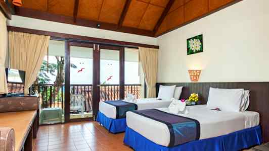 Et hotellrom med to enkeltsenger og en balkong. (AI-generert tekst)