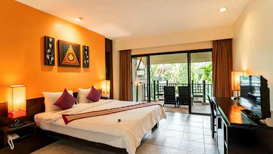 Et hotellrom med en stor seng, oransje vegger og en terrasse med stoler utenfor. (AI-generert tekst)