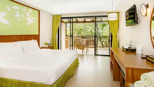 Et hotellrom med en dobbeltseng, skrivebord og utsikt mot en balkong. (AI-generert tekst)