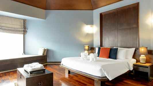 Et hotellrom med en dobbeltseng, puter i forskjellige farger på sengen og dekorasjoner av håndklær formet som dyr. (AI-generert tekst)