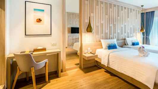 Et hotellrom med to enkeltsenger, en skrivebordshjørne og en stol. (AI-generert tekst)