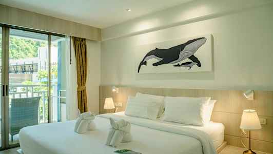 Et hotellrom med en stor seng, hvitt sengetøy og et maleri av en hval på veggen. (AI-generert tekst)