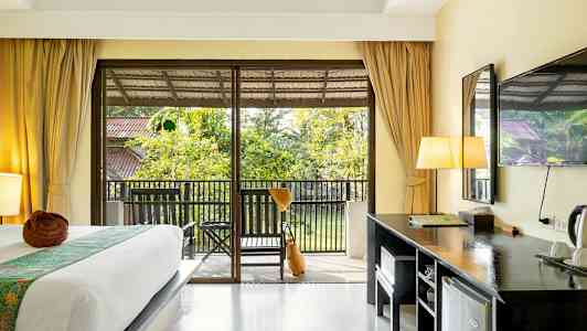 Et hotellrom med en seng, skrivebord og en balkong med utsikt over hagen. (AI-generert tekst)