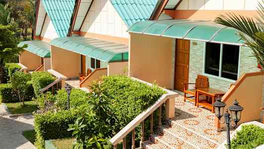 Rad av små hus med grønne tak og trapper omgitt av planter. (AI-generert tekst)