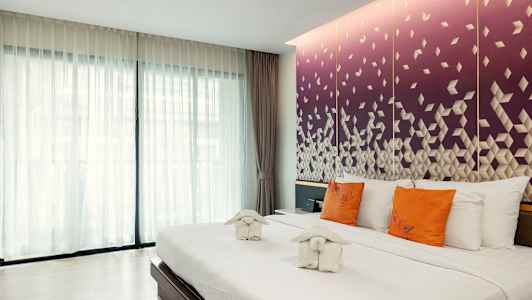 Et hotellrom med en stor seng, hvitt sengetøy, oransje puter og dekorative håndklær. Bakgrunnen viser en lilla vegg med geometrisk mønster. (AI-generert tekst)