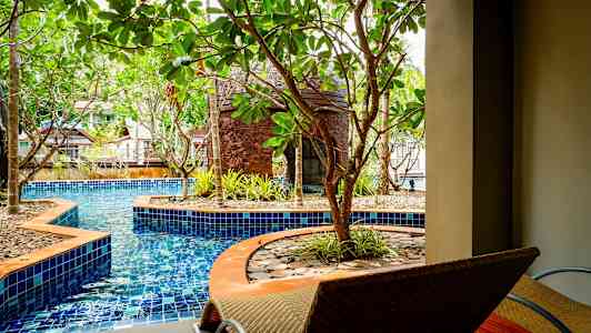 Et basseng omgitt av trær og sitteplasser. (AI-generert tekst)