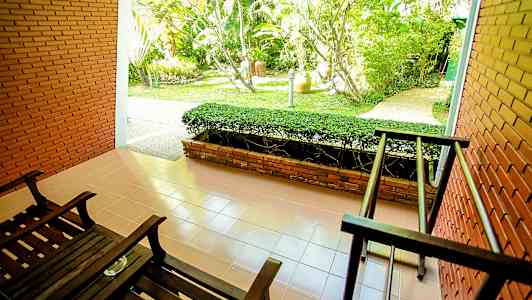 Terrasse med to mørke trestoler og utsikt mot en hage. (AI-generert tekst)