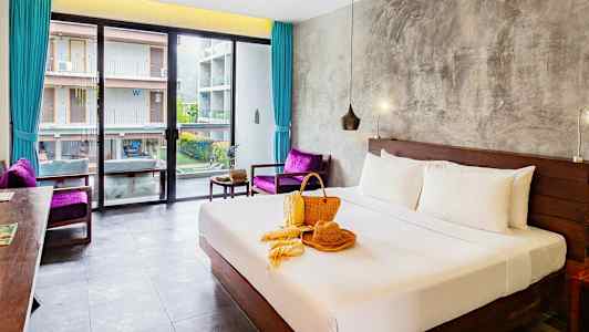 Hotellrom med en oppredd dobbeltseng, vindu mot en bygning og dekorasjon på sengen. (AI-generert tekst)