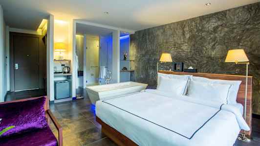 Et moderne hotellrom med en dobbeltseng, et badekar ved siden av og en elegant innredning. (AI-generert tekst)