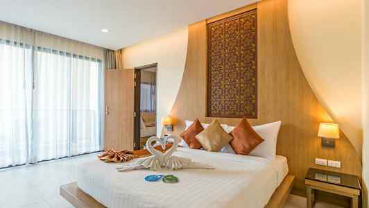 Bilde som viser et moderne hotellrom med en oppredd dobbeltseng, pyntet med dekorative puter og håndklær foldet som svaner. (AI-generert tekst)