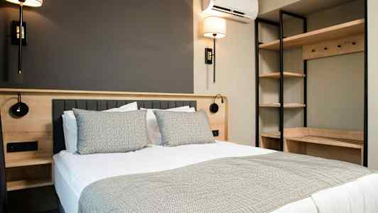 Et moderne soverom med en dobbeltseng, sengelamper og hylleoppbevaring. (AI-generert tekst)