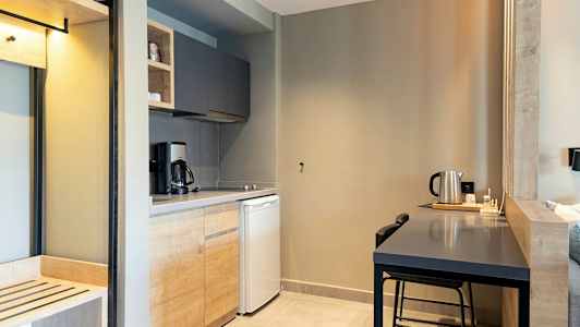 Et kjøkken med treskap, kaffetrakter, kjøleskap og et bord med vannkoker. (AI-generert tekst)