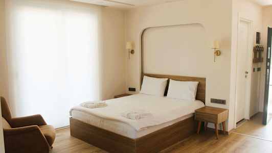 Et hotellrom med en dobbeltseng, en lenestol og et nattbord. (AI-generert tekst)