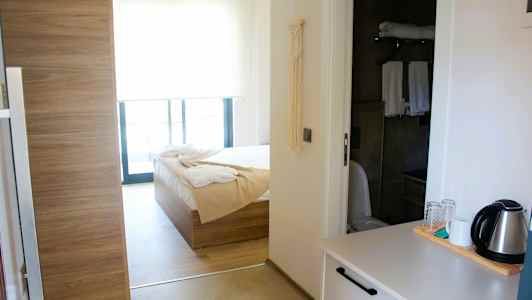 Interiør av et hotellrom med seng, bad og vannkoker på en benk. (AI-generert tekst)