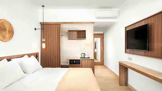 Et stilfullt hotellrom med en seng, en TV og en liten kjøkkenkrok. (AI-generert tekst)